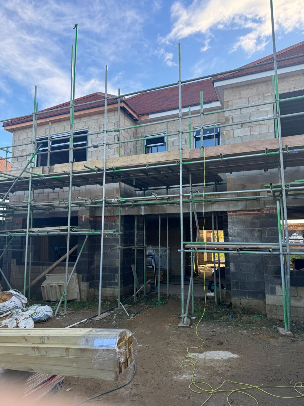 Detached new-build house in blockwork under scaffold with tiled roof